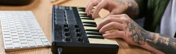 A handsome Asian man plays a MIDI keyboard in his studio. — Stock Photo