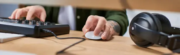 A handsome Asian man, wearing casual attire, is working in a recording studio. He is using a mixing board and computer mouse. — Stock Photo