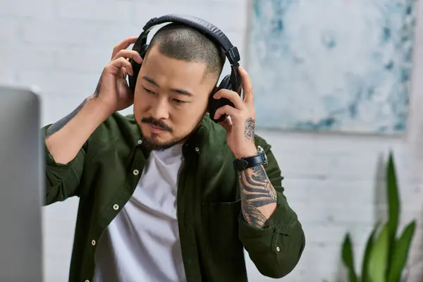 An Asian man wearing headphones adjusts his microphone in a recording studio. — Stock Photo