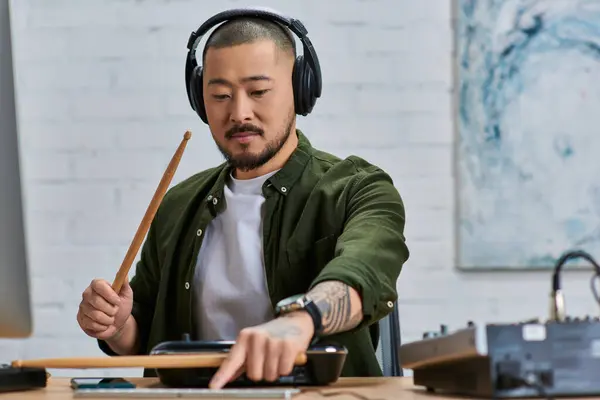 Красивый азиат в наушниках играет на барабанах в студии. — стоковое фото