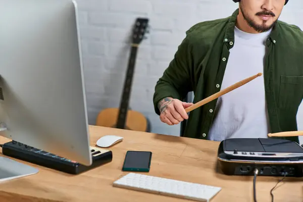 An Asian man, a multi-instrumentalist, plays drums in his studio, surrounded by music equipment. — Stock Photo