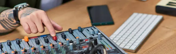 Un uomo asiatico regola i livelli sonori su un mixer. — Foto stock