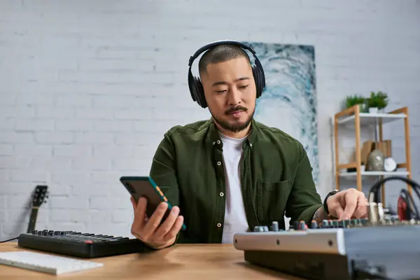 Красивый азиат в наушниках в обычной зеленой рубашке работает над музыкой в студии.. — стоковое фото