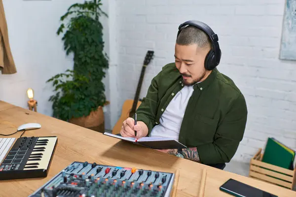 A man in casual attire is working in his studio, surrounded by musical instruments. — Stock Photo