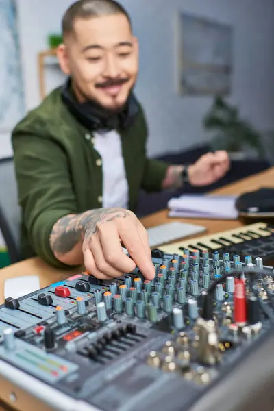 A close-up shot of a mans hand adjusting the knobs on a mixing board in a studio. — Stock Photo