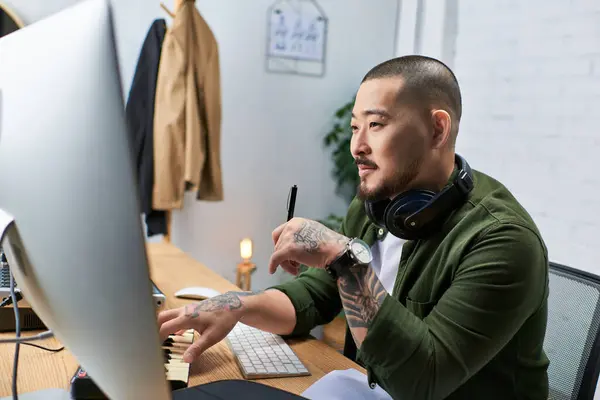 A handsome Asian man plays the keyboard while working on his music production in his studio. — Stock Photo