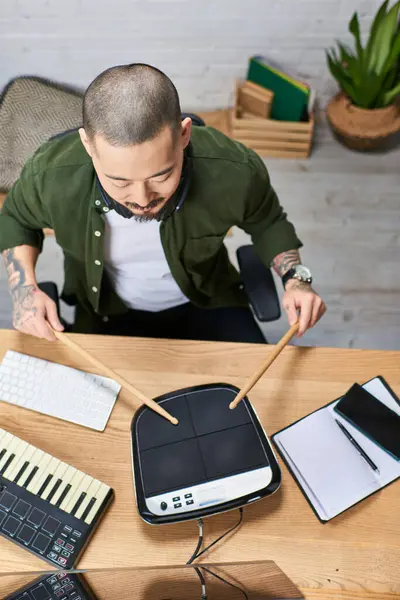 A young Asian man plays drums in a music studio. — Stock Photo