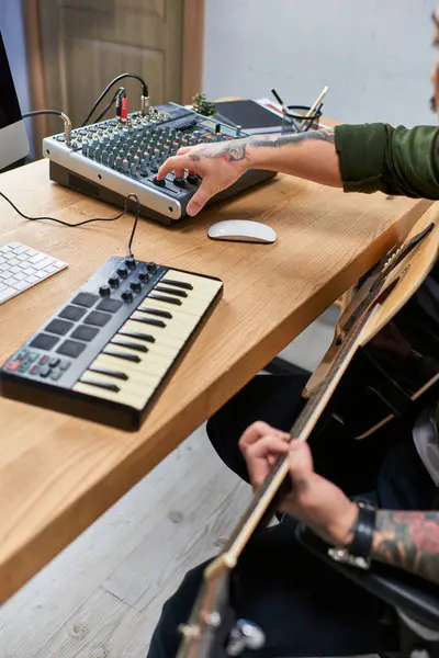 A young Asian man plays guitar and adjusts the soundboard in his studio. — Stock Photo