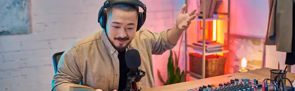A man with headphones records a podcast in his studio, looking directly at the microphone. — Stock Photo