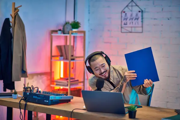 A man in a home studio setting, wearing headphones, recording a podcast. — Stock Photo