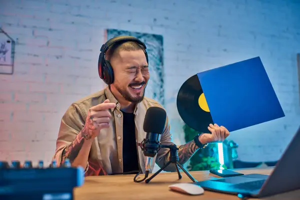 Um homem senta-se em seu estúdio, usando fones de ouvido e um microfone, gravando um podcast. — Fotografia de Stock