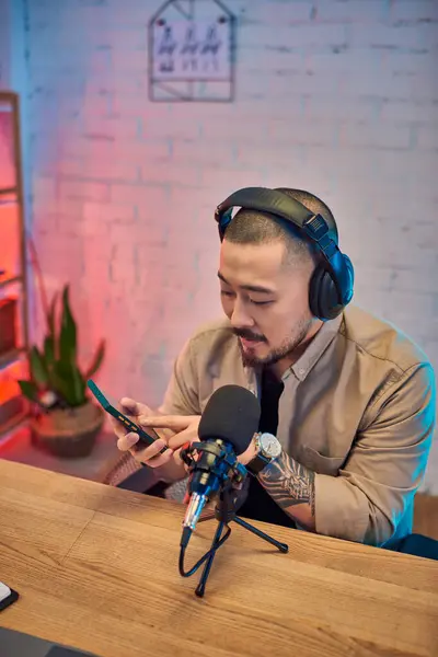 Um homem asiático bonito grava um podcast em seu estúdio. — Fotografia de Stock