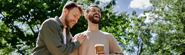 Deux hommes barbus en tenue décontractée rient ensemble dans un parc. — Photo de stock