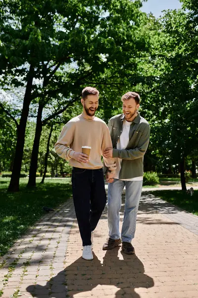 A bearded gay couple walks hand-in-hand through a park on a sunny day. — Stock Photo