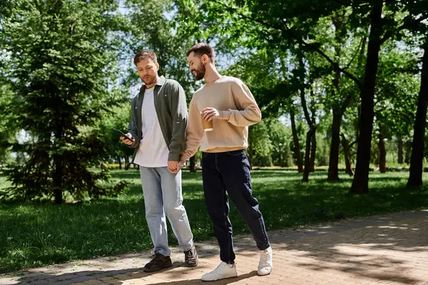 A bearded gay couple walks hand-in-hand through a lush green park, enjoying a sunny afternoon together. — Stock Photo