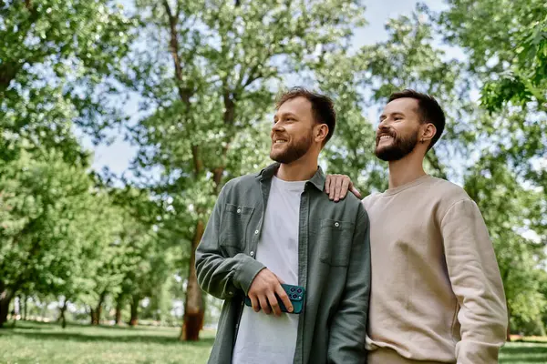 Two bearded gay men enjoy a sunny afternoon stroll in a green park. — Stock Photo