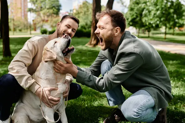Una pareja gay barbuda con atuendo casual se ríe con su perro Labrador mientras pasan tiempo juntos en un parque verde. — Stock Photo