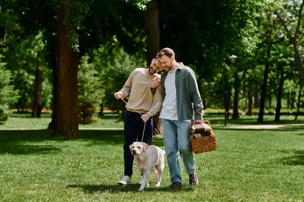 A bearded gay couple walks through a green park with their labrador dog, enjoying a sunny day. — Stock Photo