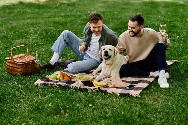 A bearded gay couple enjoys a picnic with their labrador retriever in a green park. — Stock Photo