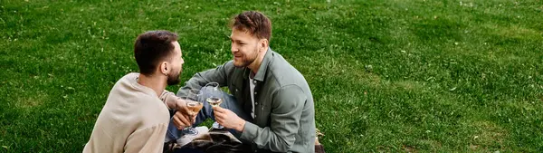 A bearded gay couple enjoys a picnic in a green park, sharing a toast — Stock Photo