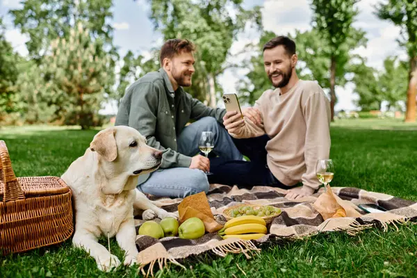 A bearded gay couple enjoys a picnic in a green park with their labrador dog. — Stock Photo