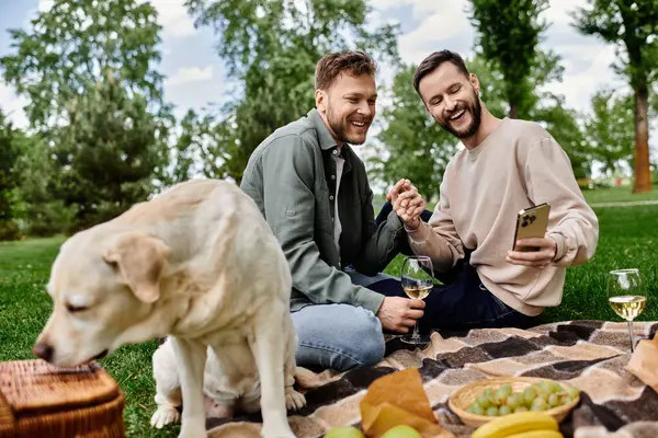 Ein bärtiges schwules Paar genießt ein Picknick mit seinem Labrador-Hund in einem grünen Park. — Stockfoto