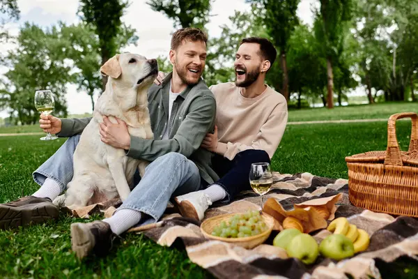 A bearded gay couple enjoys a relaxing picnic in a green park with their labrador retriever. — Stock Photo