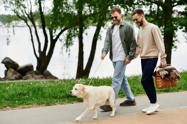 Two bearded gay men walk with their labrador retriever dog through a park. — Stock Photo