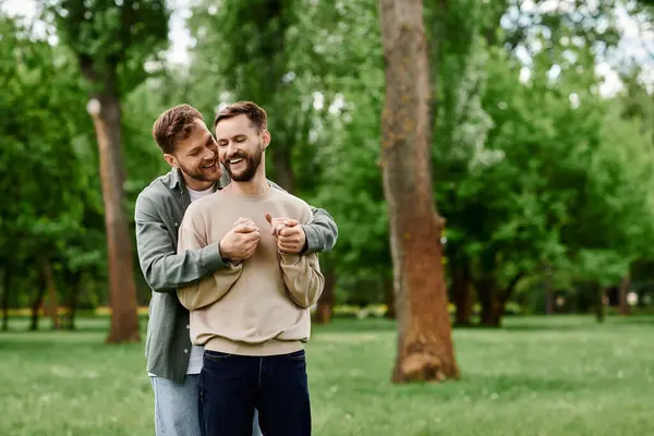 Dois homens barbudos num parque, um segurando o outro, rindo juntos. — Fotografia de Stock