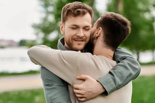 Two bearded men embrace in a green park. — Stock Photo