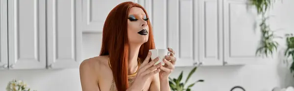 A glamorous drag diva enjoys a cup of tea in a modern kitchen. — Stock Photo