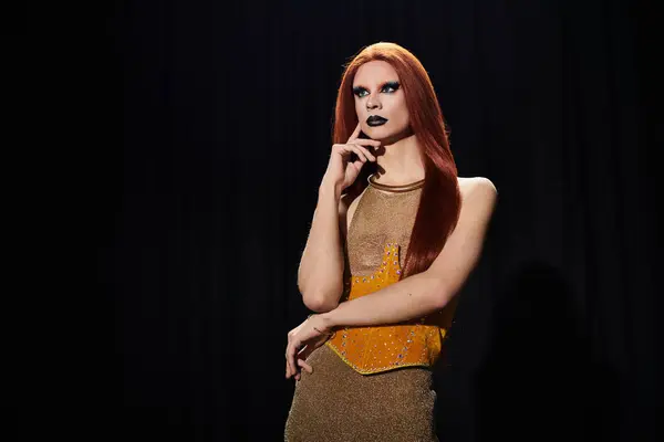 A drag queen in a glamorous outfit poses against a black backdrop. — Stock Photo