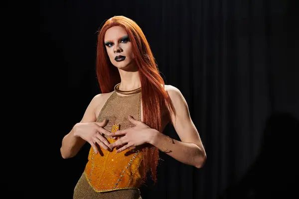 A drag diva in a glamorous gold outfit, posing against a dark backdrop. — Stock Photo