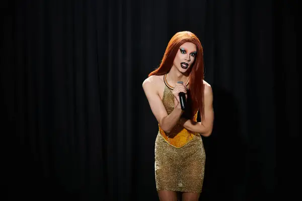 A drag queen in a dazzling gold dress performs on stage with a microphone. — Stock Photo