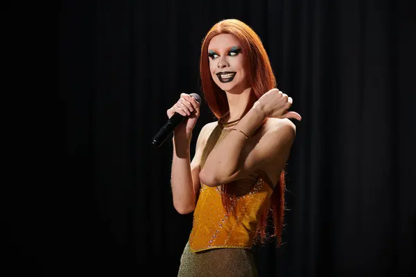 A drag diva in a gold outfit performs on stage, holding a microphone. — Stock Photo