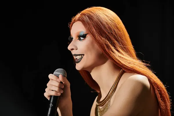 Uma diva drag com cabelo vermelho e maquiagem ousada segura um microfone, pronto para executar. — Fotografia de Stock