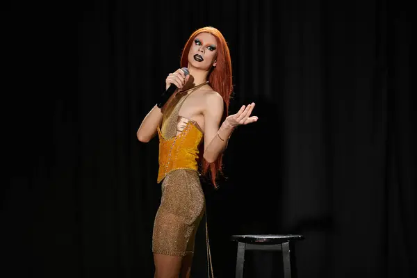 A drag performer in a shimmering gold dress takes the stage, microphone in hand. — Stock Photo