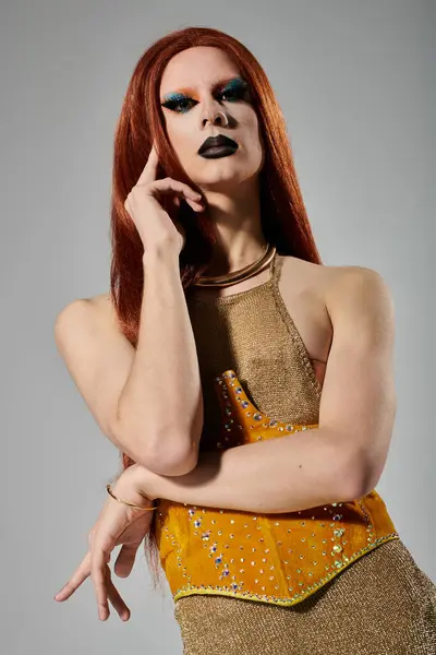 A drag queen with long red hair and bold makeup poses in a shimmering gold outfit. — Stock Photo