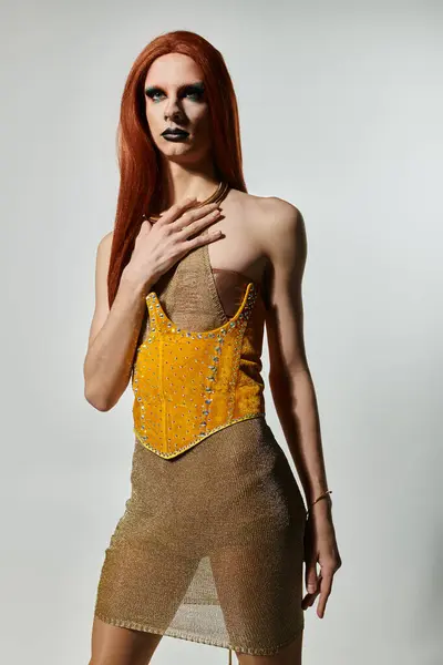 A drag diva with long red hair poses in a revealing gold dress. — Stock Photo