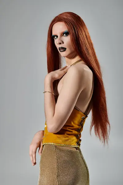 A drag queen with long red hair and bold makeup poses in a glamorous gold outfit. — Stock Photo