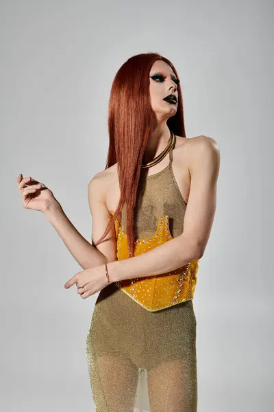 A drag queen in a shimmering gold dress poses against a white backdrop. — Stock Photo