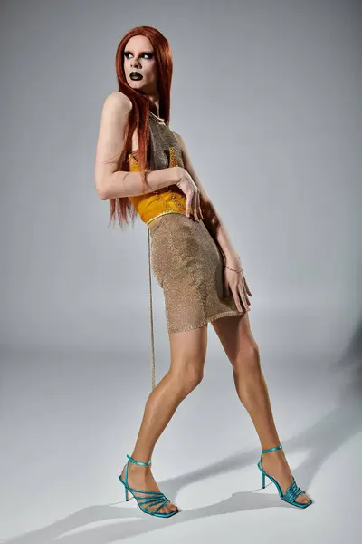 A drag queen poses in a shimmery gold dress and turquoise heels. — Stock Photo