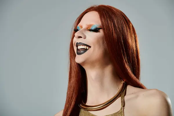 Una drag queen con lunghi capelli rossi e trucco colorato ride radiosamente. — Foto stock