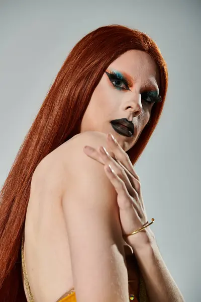 Una diva de arrastre con el pelo largo y rojo posa para un retrato en negrita maquillaje. - foto de stock