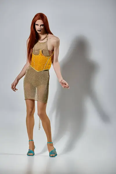 A glamorous drag queen poses in a sparkling gold dress and matching heels. — Stock Photo