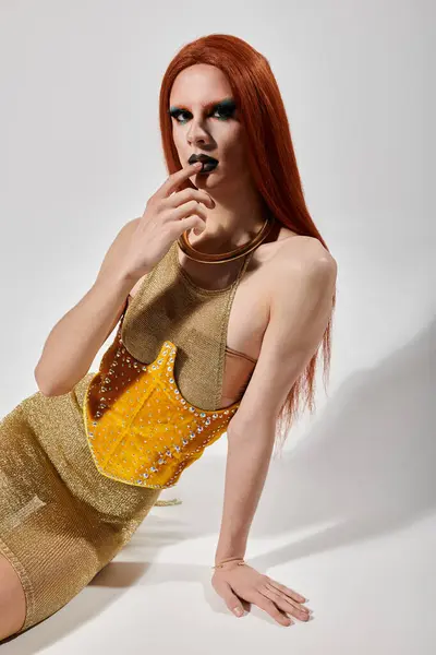 Une drag queen pose dans une tenue dorée, mettant en valeur leur style féroce et leur maquillage. — Photo de stock