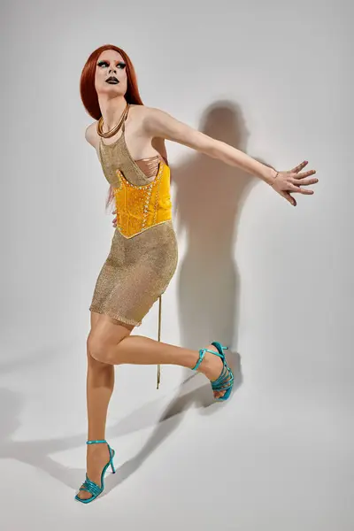 A drag queen poses in a shimmering gold dress and turquoise heels. — Stock Photo