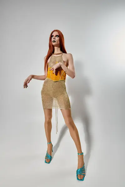 Una drag queen posa con un vestido dorado y brillante. - foto de stock