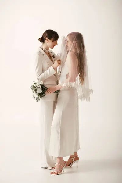 Duas jovens mulheres de traje branco se reúnem durante sua cerimônia de casamento. — Fotografia de Stock