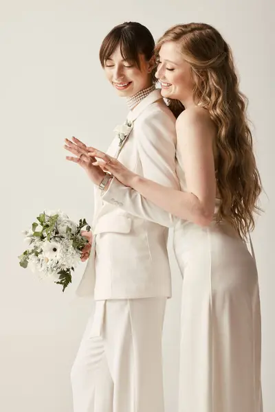 Two brides in white wedding attire embrace and smile, celebrating their love. — Stock Photo